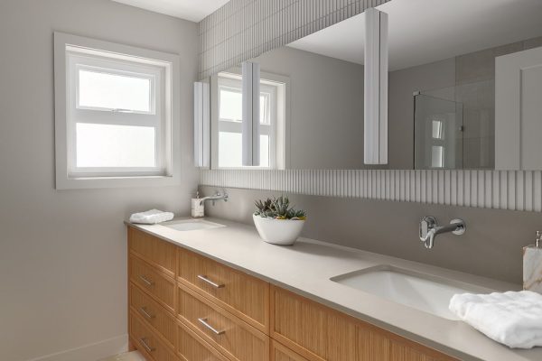 Double sink vanity with wood drawers and tile mirror detail