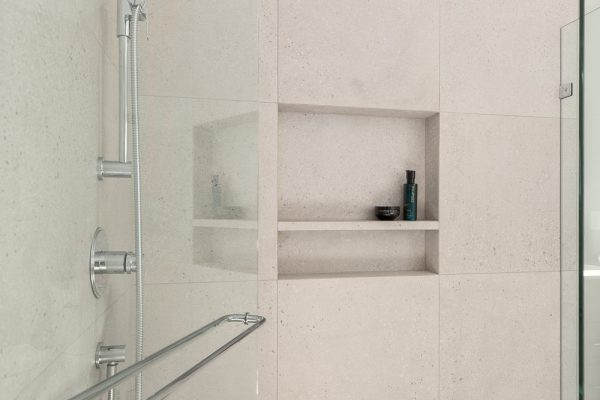 Recessed shower niche with personal care products in speckled tile wall