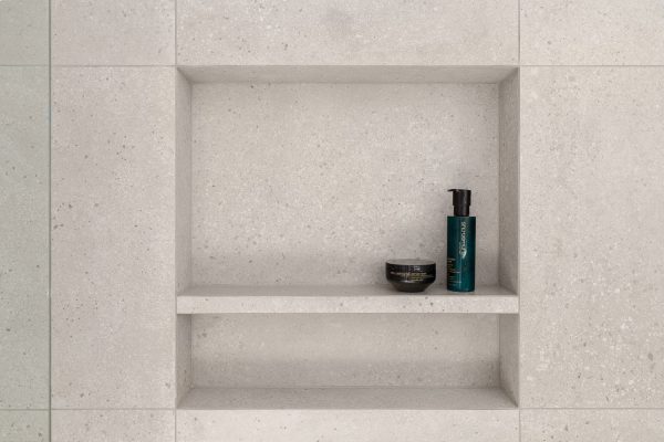Recessed tiled shower niche in speckled tile wall