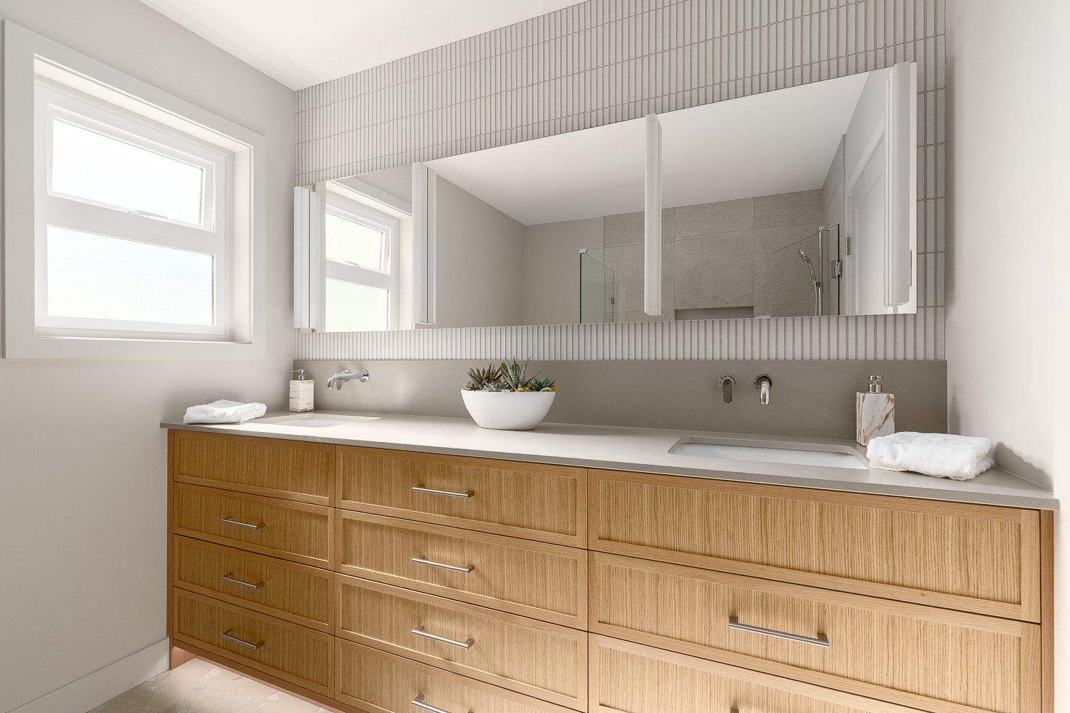 Modern bathroom renovation with dual-sink vanity, wall-mounted faucets, and custom cabinetry.
