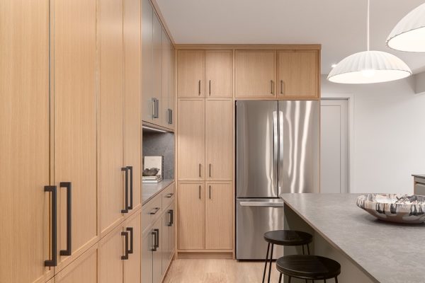 Bright, modern kitchen with full-height wood cabinetry, dark island, and pendant lighting,