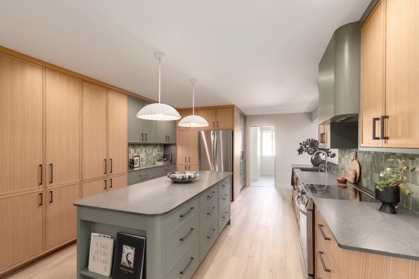 Bright, modern kitchen with full-height wood cabinetry, dark island, and pendant lighting,