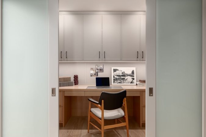 Built-in home office renovation with custom wood desk, overhead cabinetry, and integrated lighting.