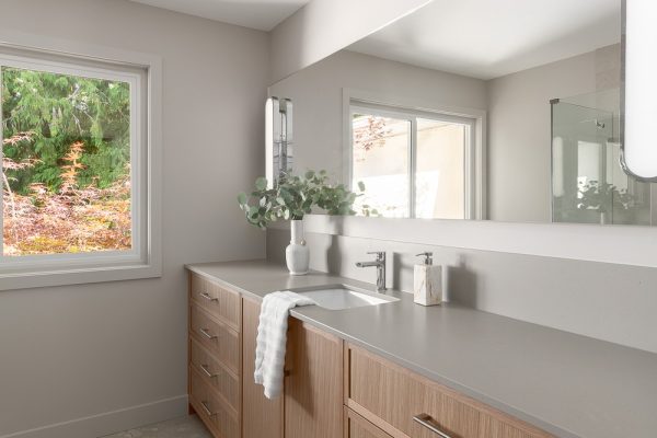 Bathroom vanity with wood cabinetry, large mirror, and natural light from two windows