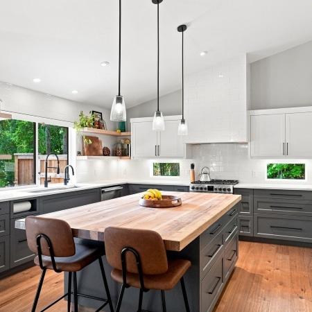 Modern West Coast kitchen with custom cabinetry, wood‑accented island, and pendant lighting, built by Pickard Construction in the Parksville–Qualicum Beach area