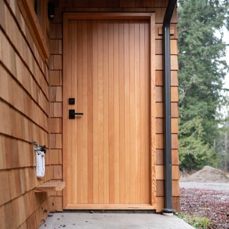 Modern wood exterior door with vertical cladding and black hardware, completed under Pickard Construction as the general contractor in the Parksville–Qualicum Beach area.