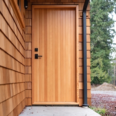 Modern wood exterior door with vertical cladding and black hardware, completed under Pickard Construction as the general contractor in the Parksville–Qualicum Beach area.